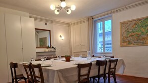 A dining room with a large table set for six, surrounded by wooden chairs. There is a window with curtains, a map on the wall, and a ceiling light fixture. - Cozy townhouse with garden near Argenton-sur-Creuse (Saint-Marcel)