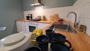A compact kitchen with a stove, sink, and a box of Citron & Cagêmeire Infusion Bio. - Cozy townhouse with garden near Argenton-sur-Creuse (Saint-Marcel)