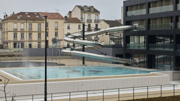 Un edificio moderno con piscina y una estructura de tobogán de agua única.