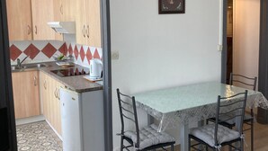Una cocina compacta con armarios de madera, un refrigerador blanco, una tetera y un salpicadero con diseño.