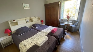 A double room with two beds, a small table, a chair, a window with a view, and a wooden wardrobe. - Charming farmhouse with garden near Lake Eguzon (Gournay)
