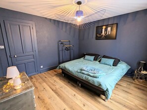 Ein Schlafzimmer mit Bett, Kleiderschrank, einer Pendelleuchte und einem Bild an der Wand.