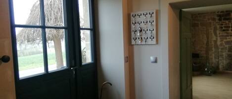A room with a large window, a wall-mounted key rack, and a stone wall in the background.