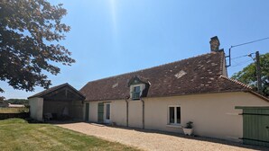 A two-story house with a tiled roof, a small attached garage, and a gravel driveway.