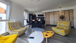 Un salon moderne avec un canapé, des fauteuils, une petite table et un ventilateur.