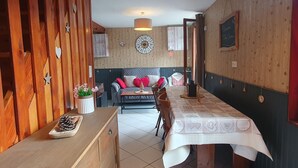 Una stanza accogliente con un tavolo da pranzo in legno, un divano con cuscini, una sveglia a muro e una pianta decorativa.
