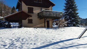 Una casa a due piani con un balcone, immersa in un paesaggio innevato.
