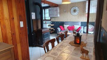 Een gezellige woonkamer met een open haard, een eettafel en een bank met decoratieve kussens.
