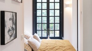 Une chambre à coucher avec un lit, une fenêtre et des œuvres d’art accrochées aux murs.