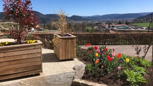 A garden with wooden planters and a variety of flowers, a wooden fence, and a view of a town and hills in the distance. - Renovated house near Vosges, ideal for outdoor activities (Saint-Nabord)