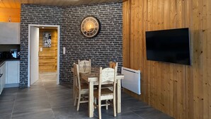 Une cuisine moderne avec un mur en briques, un plafond en bois et un coin repas comprenant une table et des chaises en bois.