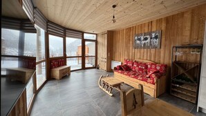 L’intérieur d’un chalet accueillant, avec un plafond en bois, un canapé rouge à motifs, un banc en bois et une table à manger.