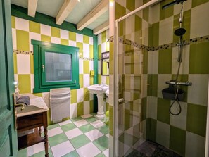 Ein Badezimmer mit Schachbrettfußboden, einem Waschbecken, einem Spiegel und einer Duschkabine.
