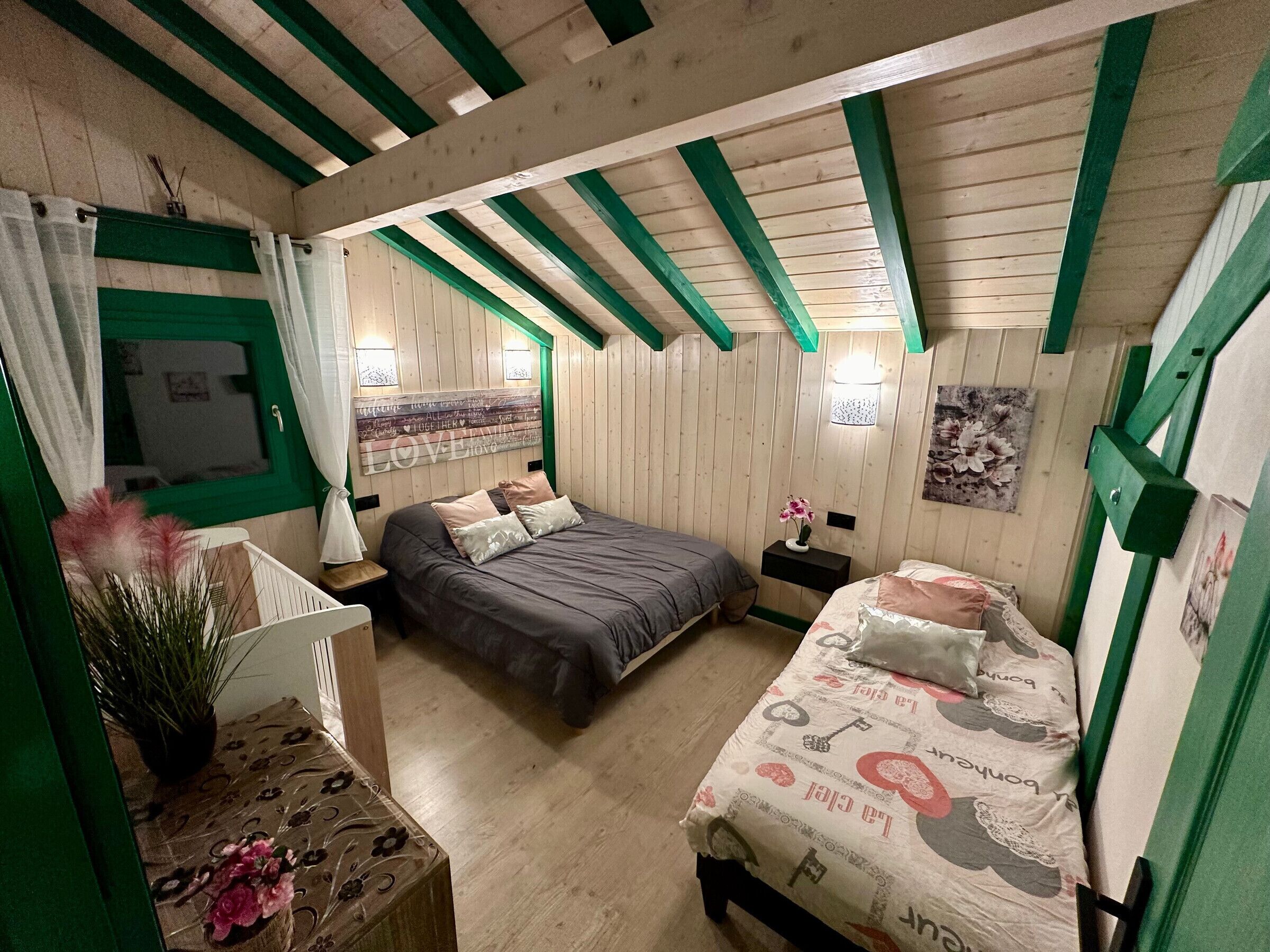 A cozy room with two beds, a small table, and a window with curtains.