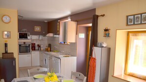 Une cuisine compacte avec un coin repas, comprenant une table pour deux personnes, un four à micro-ondes, un four et un lave-linge.