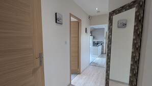 A hallway with wooden doors, a mirror, and a kitchen visible in the distance.