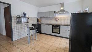 Moderni keittiö, jossa on mikroaaltouuni, leivänpaahdin, uuni ja musta jääkaappi. Keittiössä on myös kaksi baarijakkaraa ja pesuallas.