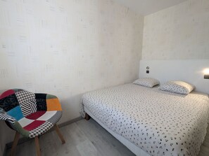 Une chambre à coucher avec un lit, une chaise et un mur orné d’un motif.