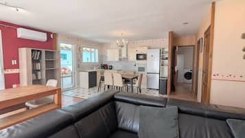 A modern living room with a black leather sofa and a dining area with a wooden table and chairs.