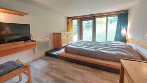 A bedroom with a bed, a TV, a desk, and a window with curtains. - Calm duplex near slopes with balcony (Les Arcs 1800)