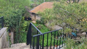 Eine steile Steintreppe führt zu einem Haus mit Ziegeldach, umgeben von üppiger Vegetation und einem kleinen Garten.