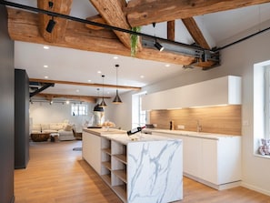 A modern kitchen with marble countertops, wooden beams, and pendant lighting. - Modern loft with old-world charm, air-conditioned, near Stanislas Square (Nancy)