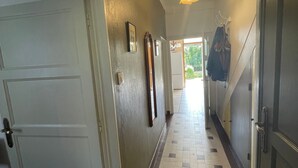 A hallway with a tiled floor, a door on the left, and a coat rack on the right. - Charming farmhouse with private garden and pond, perfect for exploring Berry (Gournay)