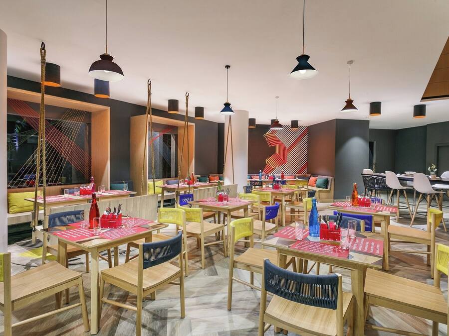 A modern restaurant with multiple dining areas, wooden tables, and chairs.