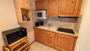 Une cuisine compacte avec des meubles en bois, un four à micro-ondes, un évier et un réfrigérateur à vin.