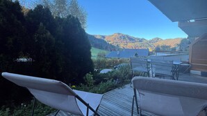 Une terrasse dotée de chaises en osier, offrant une vue sur un paysage montagneux.