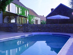 Une piscine avec des murs en pierre et une terrasse en bois.
