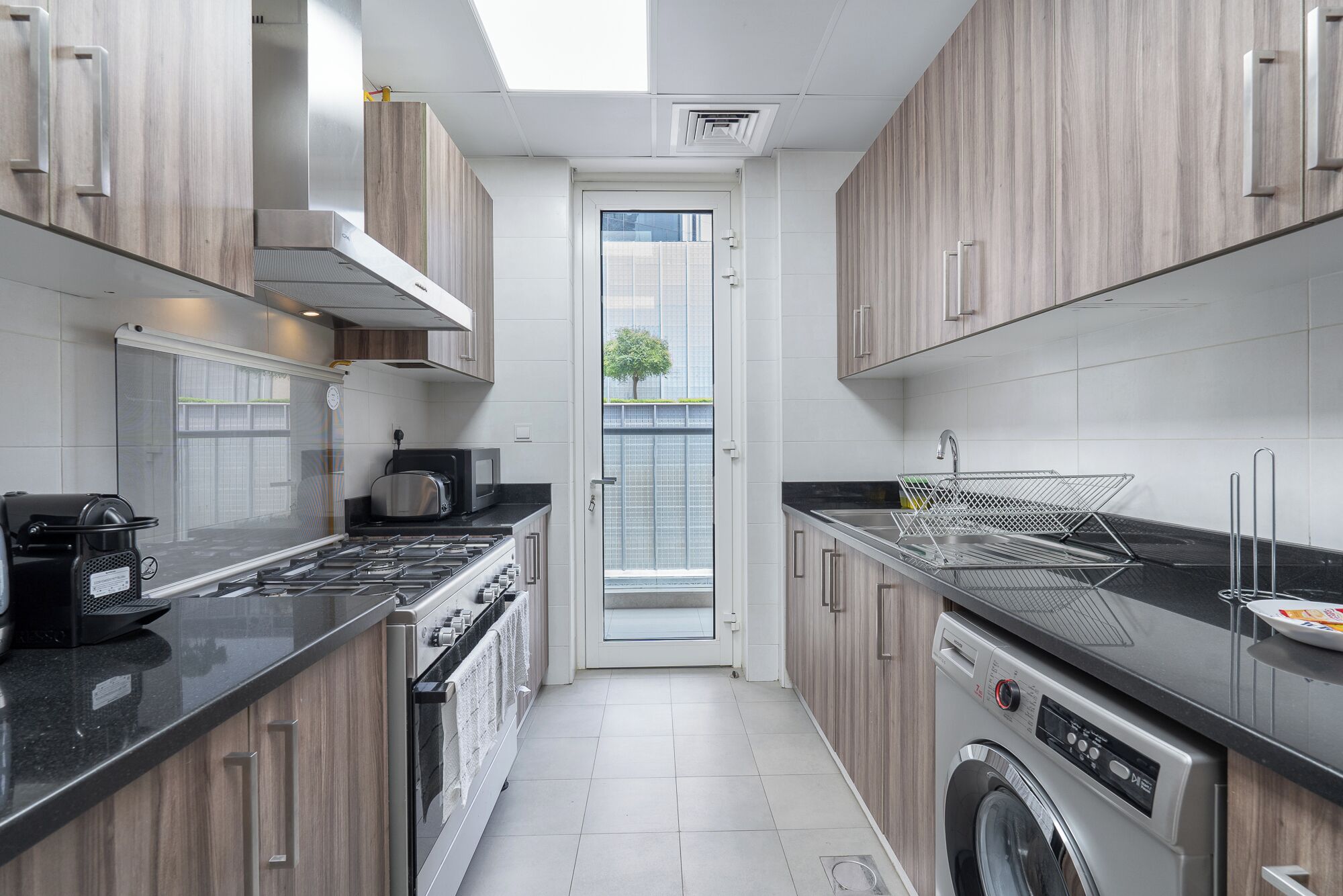 A modern kitchen with a stove, microwave, and washing machine.