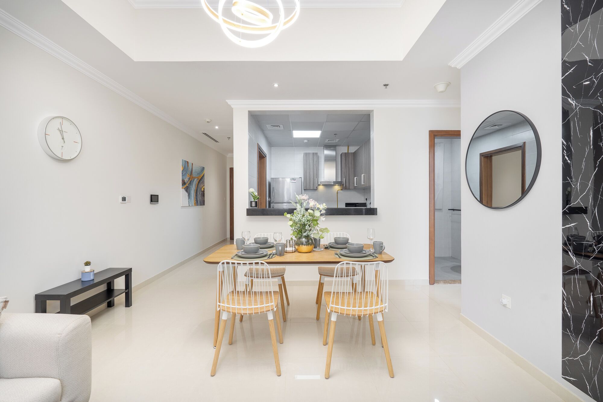 A modern dining room with a wooden table, four chairs, and a vase of flowers.