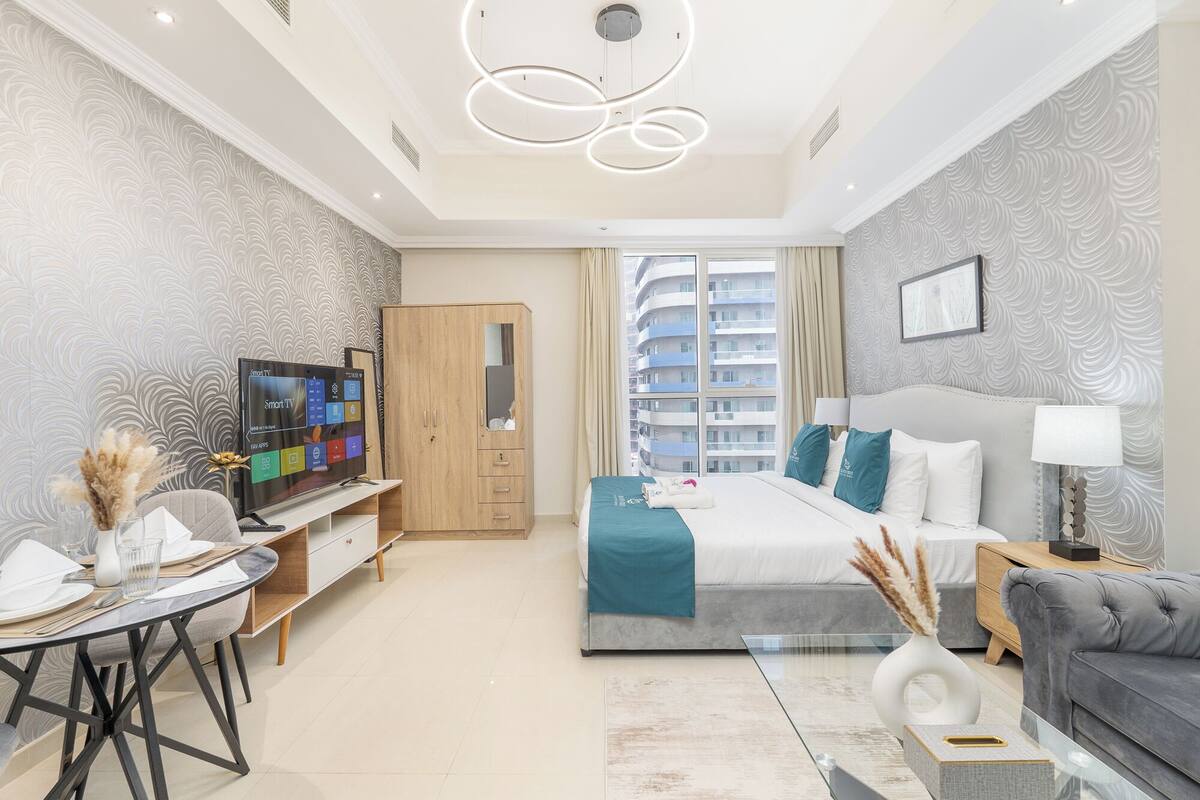 Une chambre d’hôtel moderne équipée d’un lit, d’une table de chevet, d’une lampe et d’un téléviseur affichant une interface de télévision intelligente.