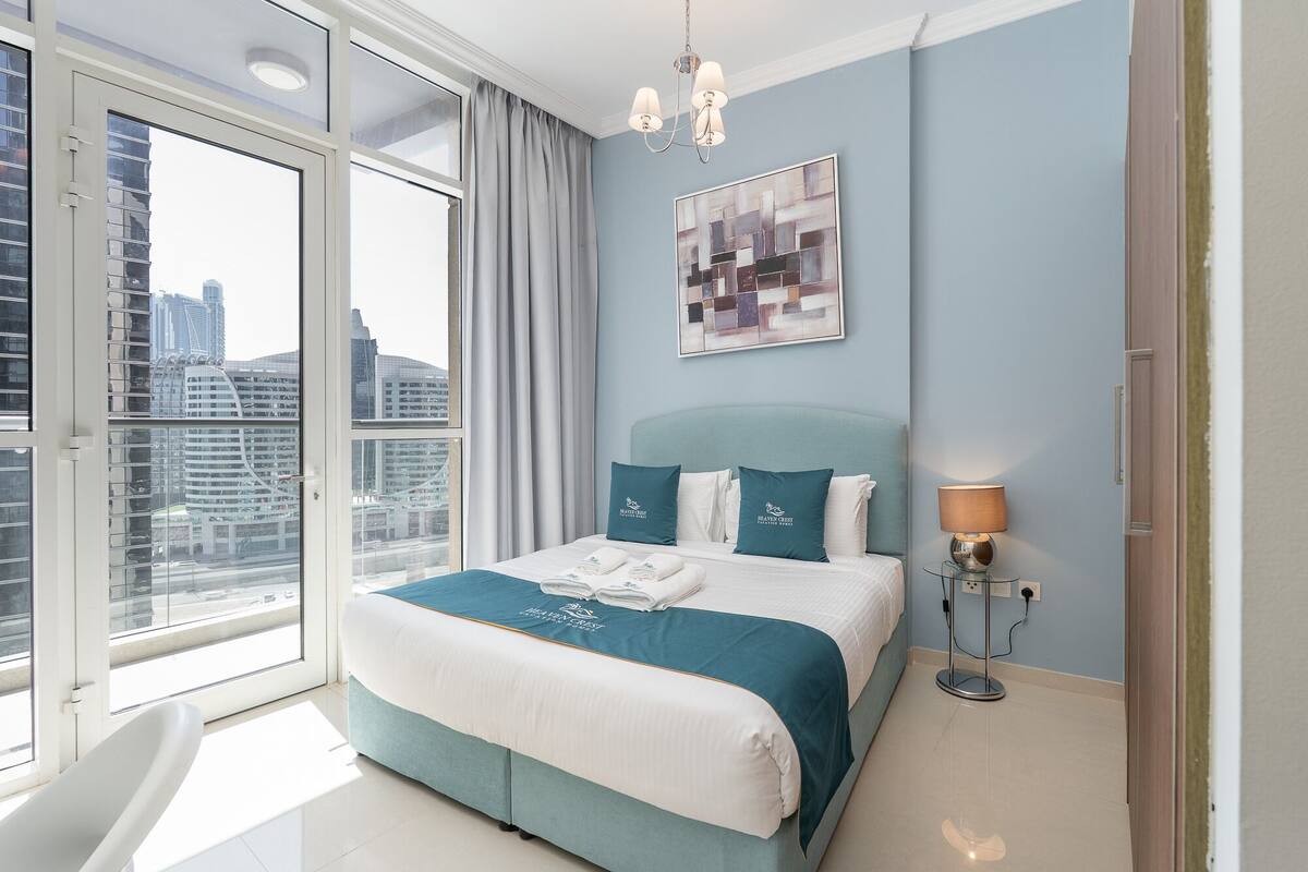 Une chambre moderne avec un grand lit, une vue sur la ville et un lustre.
