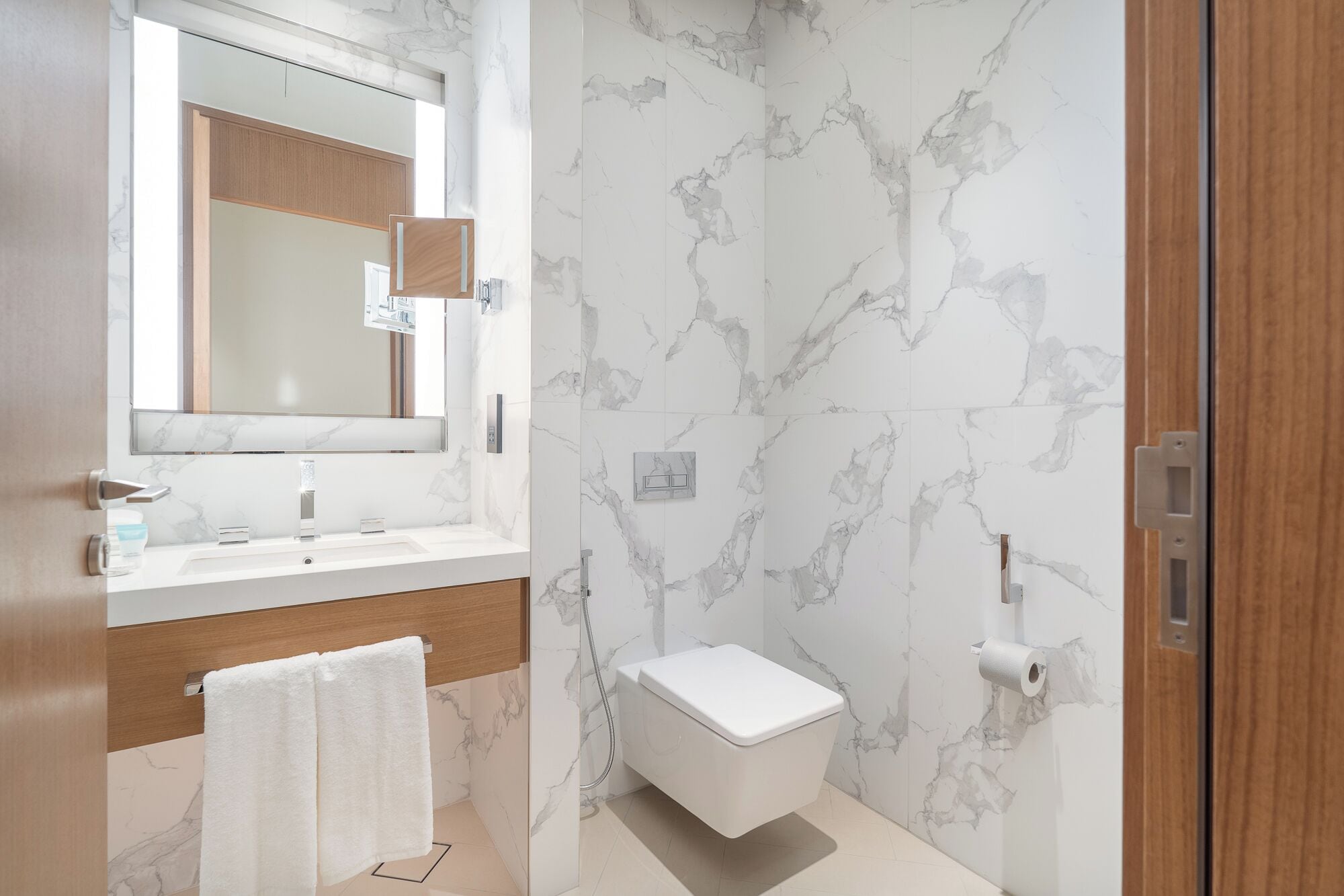 Une salle de bain moderne avec un pare-baignoire en marbre, un meuble-lavabo en bois, des toilettes et une douche à paroi de verre.