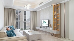 Una sala de estar moderna con un sofá color beige, una mesa de centro y un televisor montado en la pared con un estante de madera debajo.