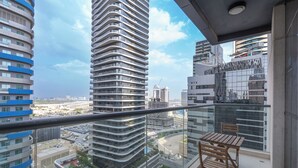 Un balcón con una mesa y sillas de madera, con vistas a un paisaje urbano de edificios modernos.