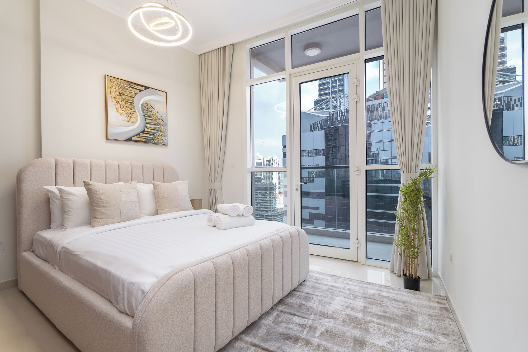 A modern bedroom with a large bed, a city view, and a decorative painting.