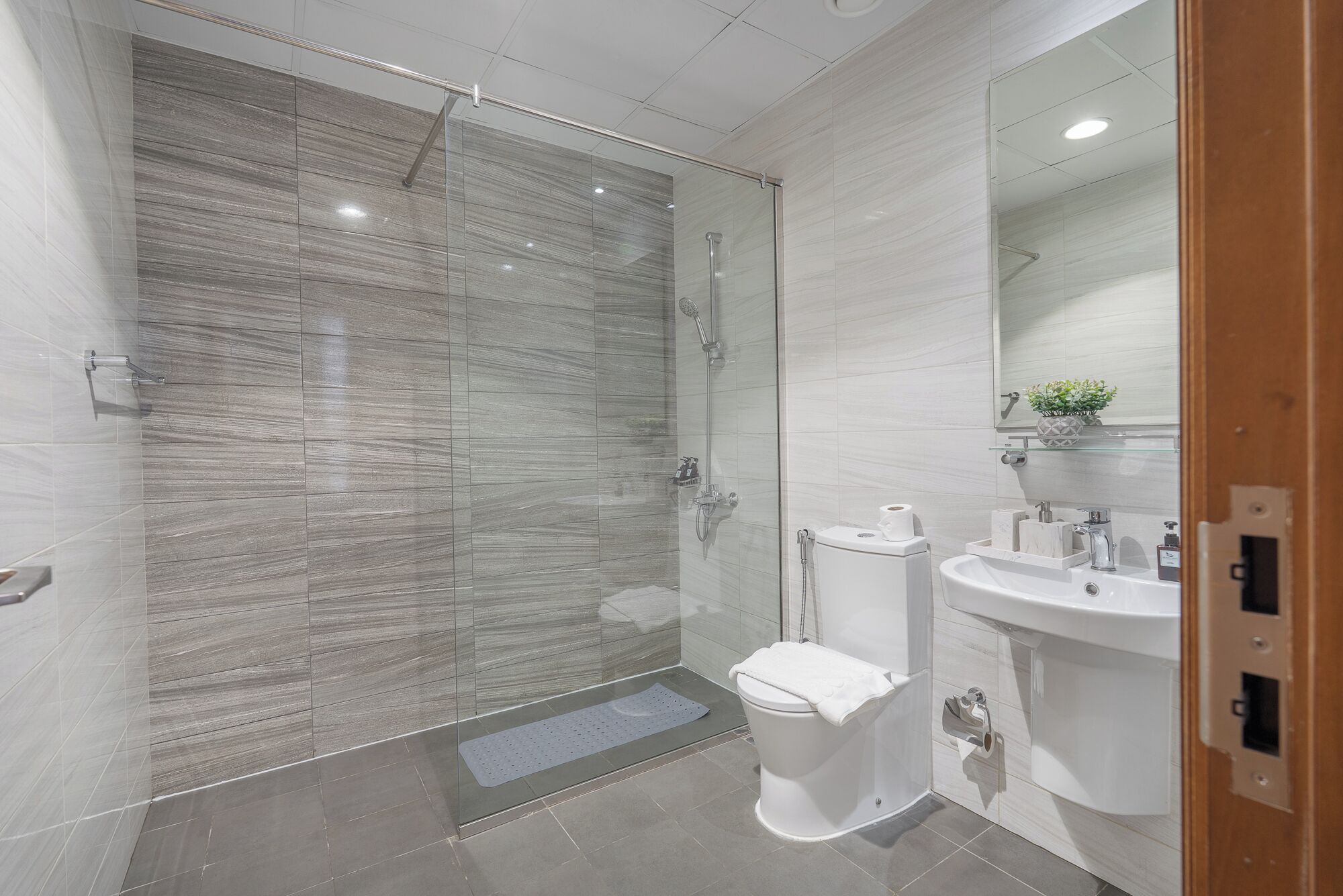 Un bany modern amb una cabina de dutxa de vidre, un vàter i un lavabo amb un mirall a la part superior.