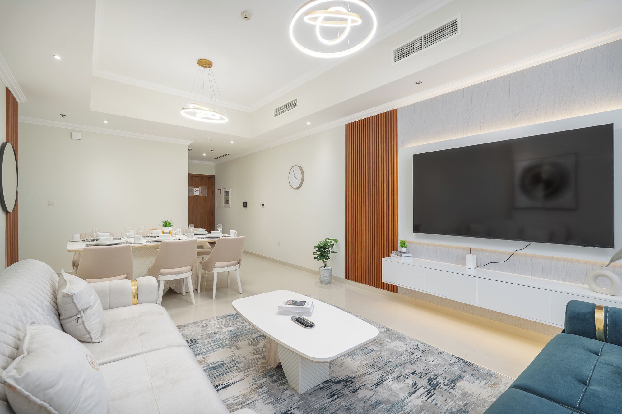 A modern living room with a sofa, coffee table, TV, and dining area.
