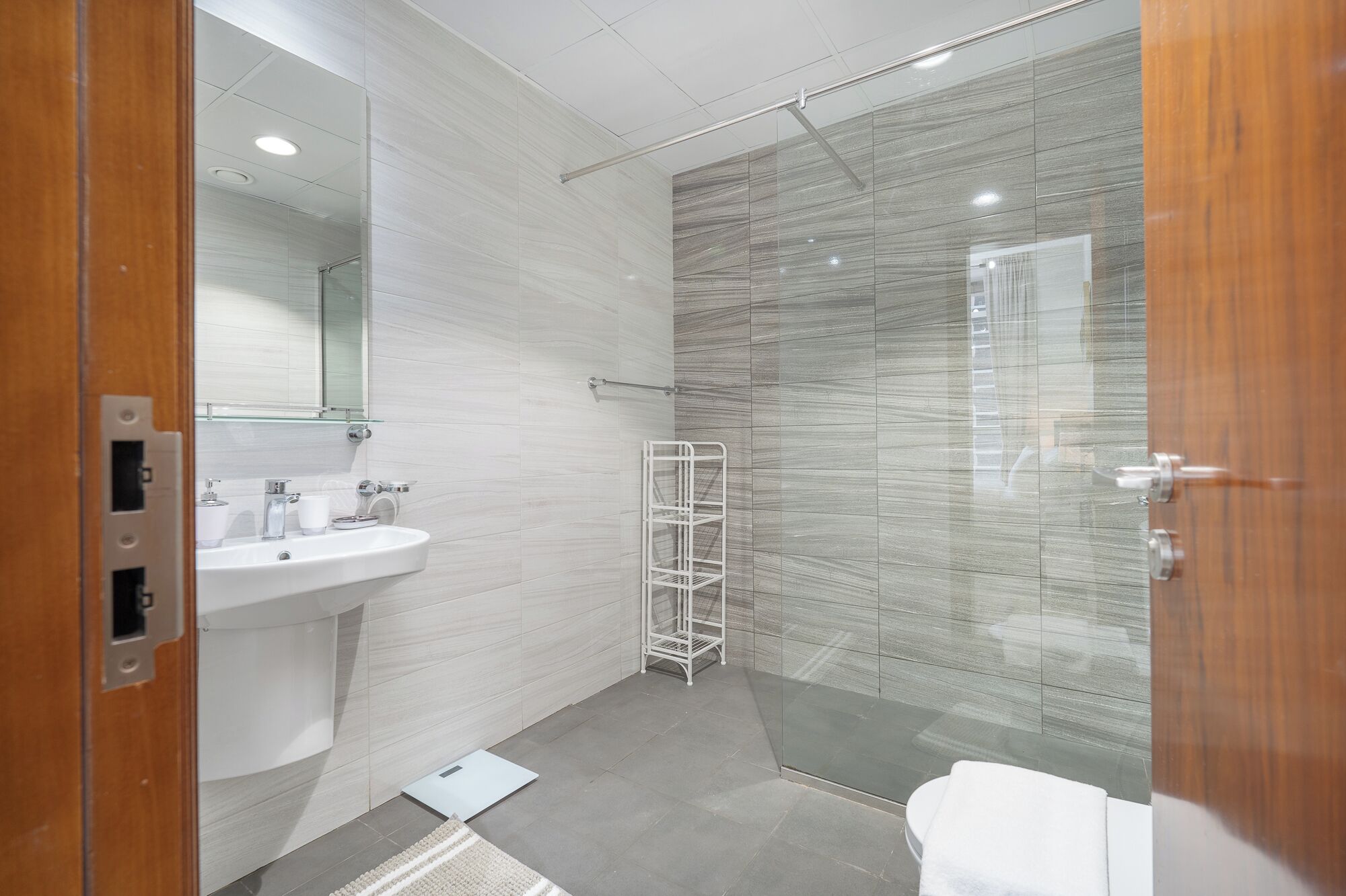 A modern bathroom with a white sink, mirror, and toilet.