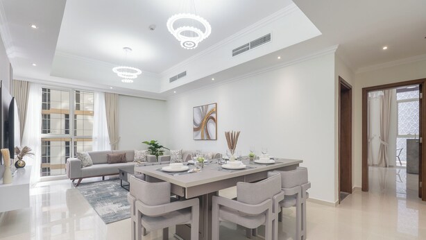 A modern dining area with a long table, multiple chairs, and a chandelier. - Heaven Crest Vacation Homes Downtown - Studio, 1, & 3 Bedroom Suites 2 minute walk to Dubai Mall and Burj Khalifa (Dubai)