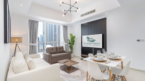 A modern living room with a sofa, a dining table set for four, and a large window with a city view. - Heaven Crest Vacation Homes Downtown - Studio, 1, & 3 Bedroom Suites 2 minute walk to Dubai Mall and Burj Khalifa (Dubai)