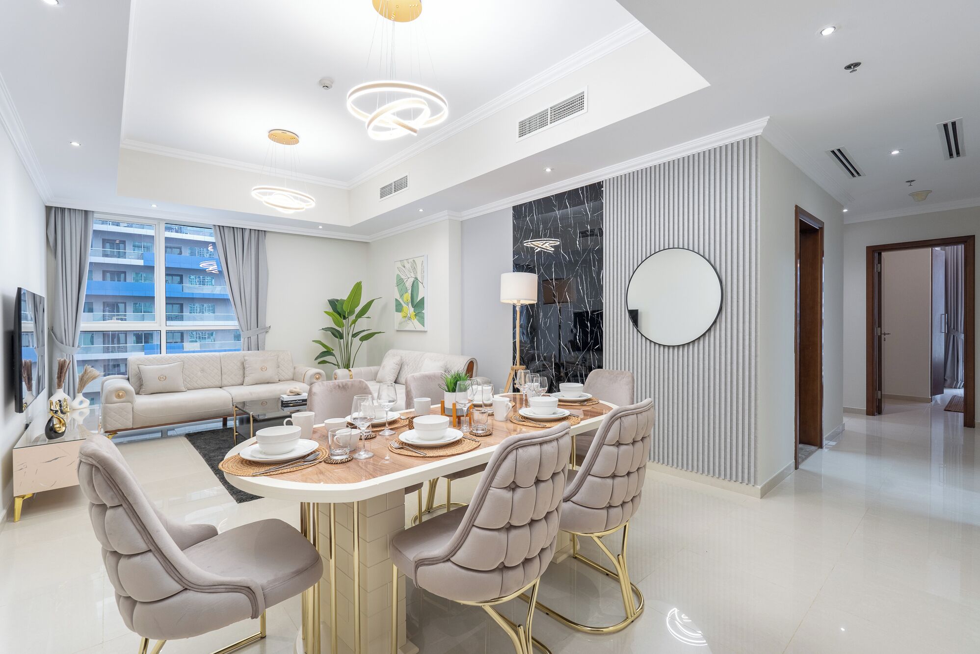 Een moderne eetruimte met een ronde tafel, comfortabele stoelen en een kroonluchter.