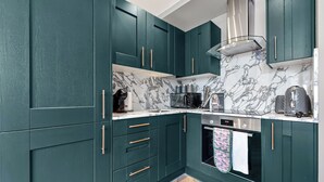 A kitchen with teal cabinets, a microwave, a coffee maker, and a toaster.