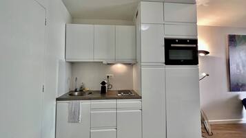 Een koelkast, kookgerei, borden en bestek, een eettafel