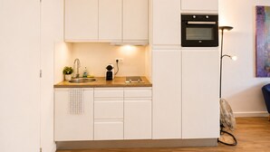 Eine kleine Küche mit weißen Schränken, einem Backofen, einer Spüle und einer Arbeitsplatte.