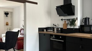 Eine moderne Küche mit schwarzen Schränken, einer Holz Arbeitsplatte und einem eingebauten Backofen.