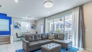 A modern living room with a sectional sofa, ottoman, and a blue patterned rug.